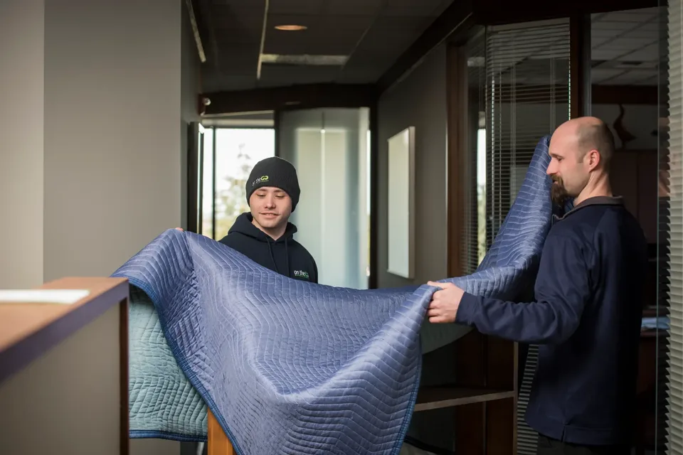 On The Go Moving crew wrapping furniture in an office